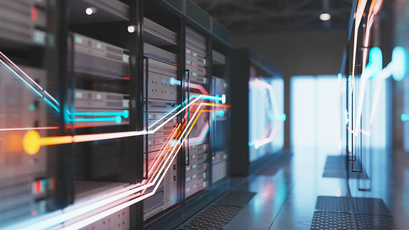 A view of a modern data center with rows of server racks. Colorful light trails suggest data transfer between servers along the aisle, leading to a bright area in the background.