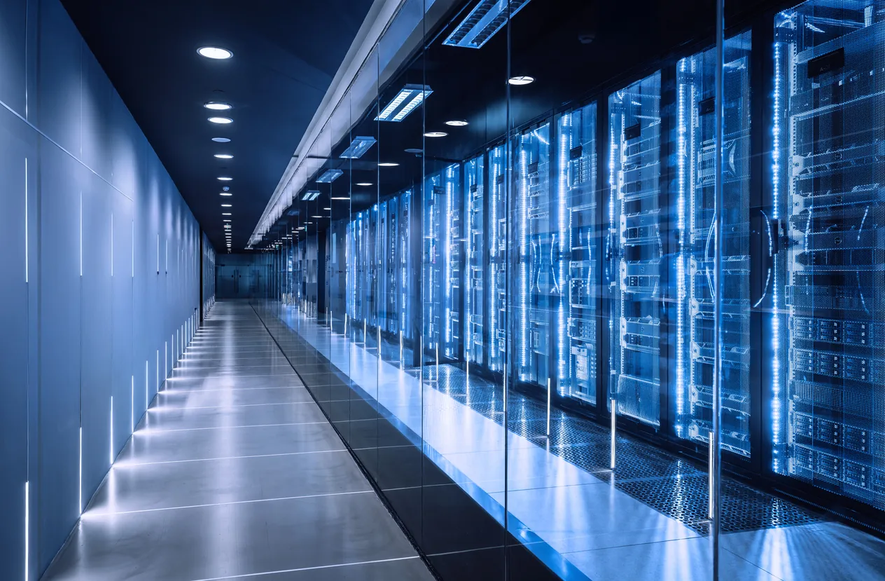 A modern data center corridor featuring rows of server racks with blue LED lights, illuminated by overhead lights in a sleek environment.